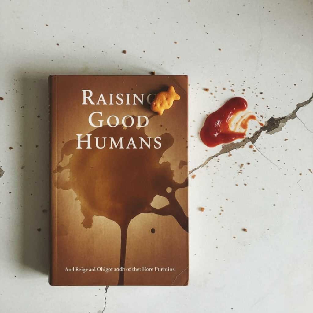 Coffee-stained "Raising Good Humans" book with goldfish cracker.